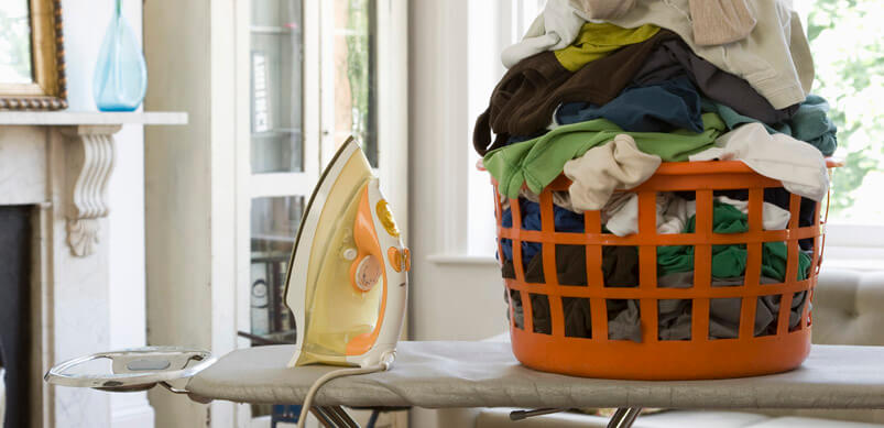 Pile Of Laundry And Iron On Ironing Board