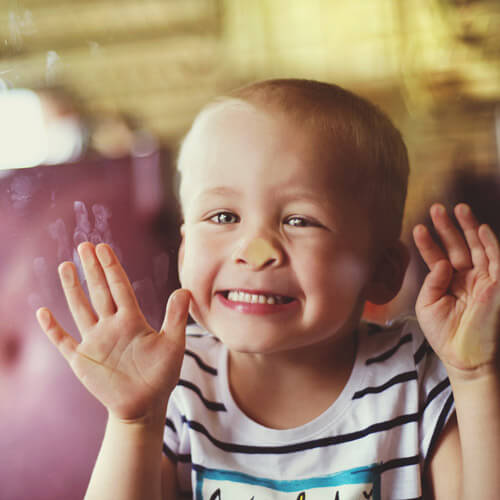 Boy Making Sticky Fingerprints On Window