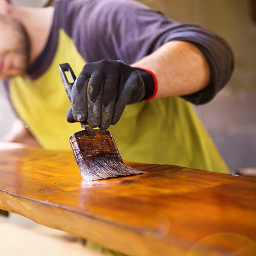 Man Varnishing Plank Of Wood