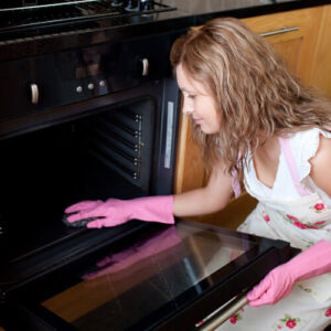 Woman Cleaning Oven After Baking