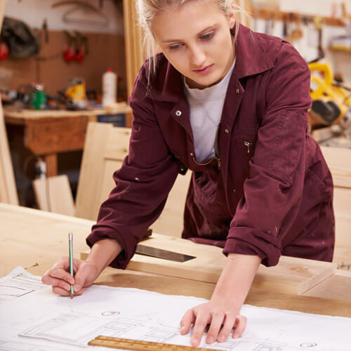 Woman Drawing Out Plans On Workbench