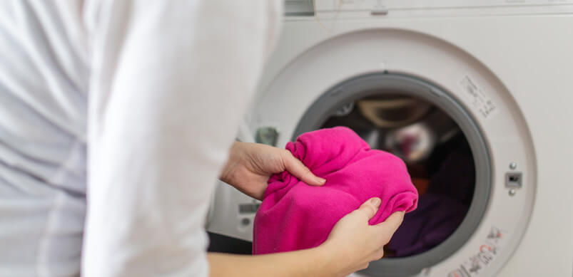 Woman Loading Clothes Into Washing Machine