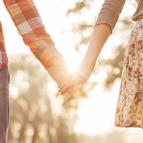 Couple Looking At The Sunset Holding Hands