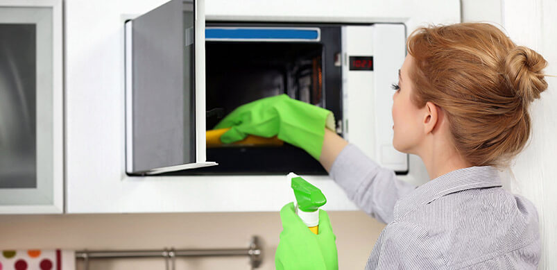 Woman Cleaning Inside Microwave