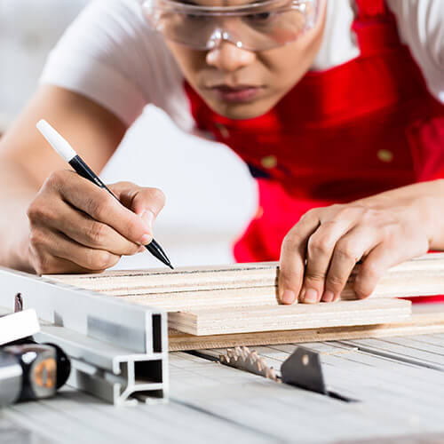 Man Marking Wood To Cut It