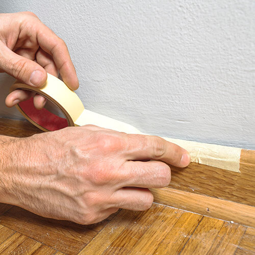 Man Putting Masking Tape On Skirting Board