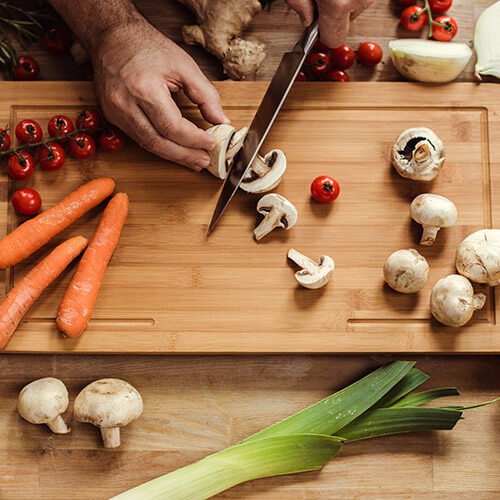 Man Slicing Mushrooms On Chopping Board