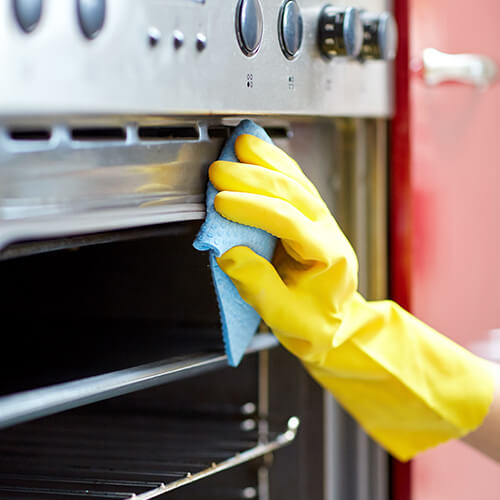 Hand in yellow glove cleaning grill