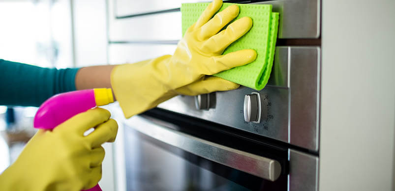 Hands in Rubber Gloves Cleaning Front Of Oven