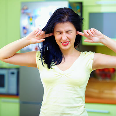 Woman With Fingers In Ears To Block Out Noise