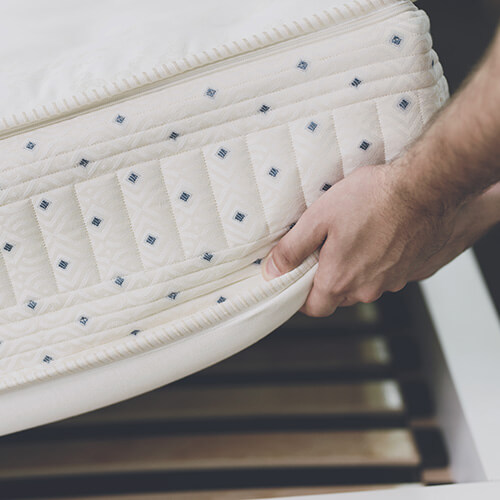 Close Up Of Hand Lifting Mattress