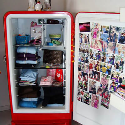 Open Broken Fridge With Folded Clothes And Photos On Door