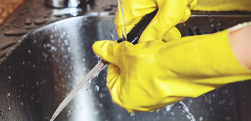 Hands In Rubber Gloves Rinsing Knife