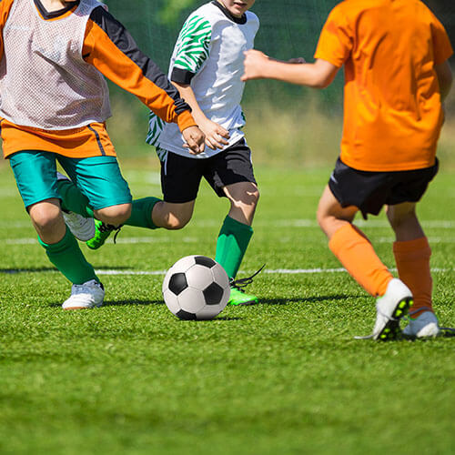 Kids Playing Football In Field 