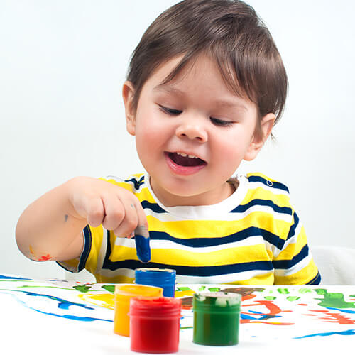 Child Using Coloured Paints On Paper