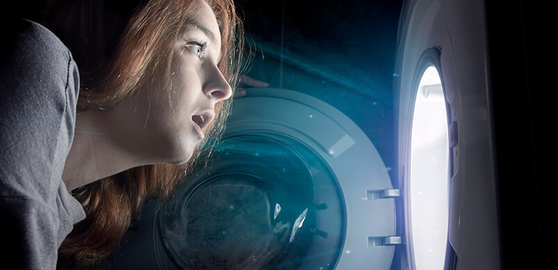 Woman Looking Into Light Inside Washing Machine. Magical