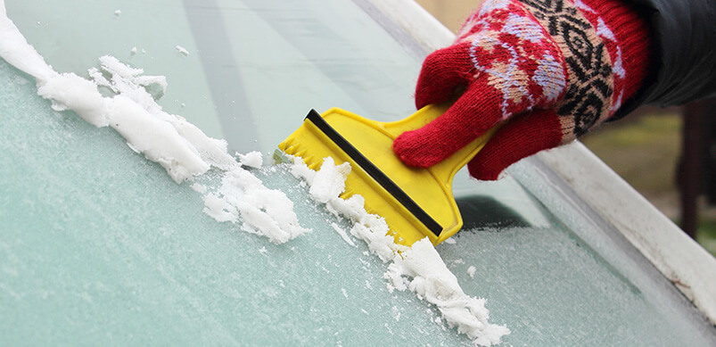 Hand In Glove Scraping Ice From Windscreen