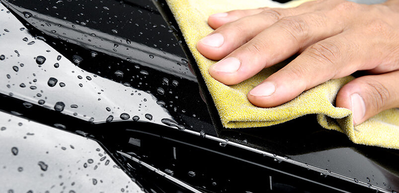 Hand Wiping Water On Black Car