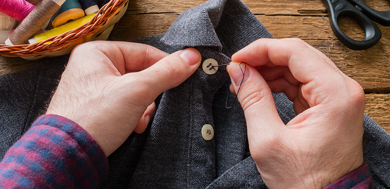 Man Sewing Button Onto Shirt