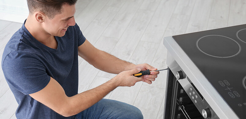 Man Repairing Oven In Kitchen