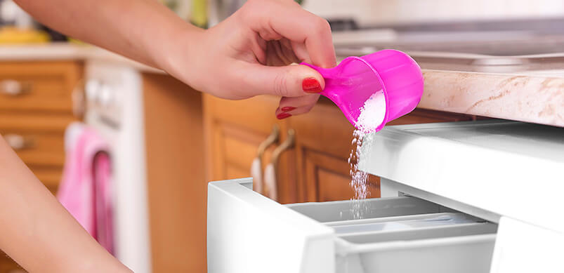 Woman Pouring Laundry Detergent Into Washing Machine