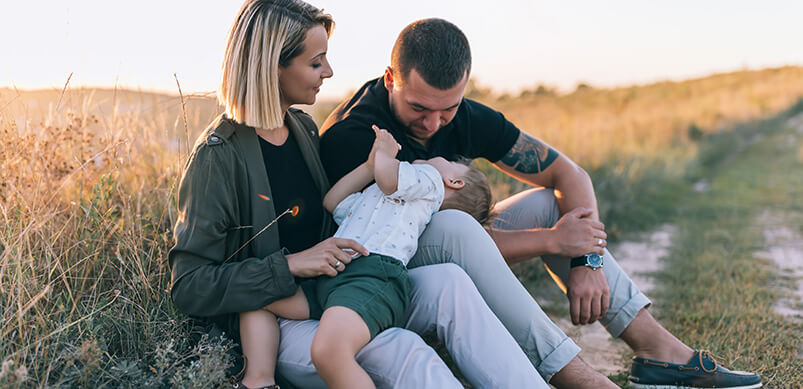 Family Sitting And Playing At Sunset