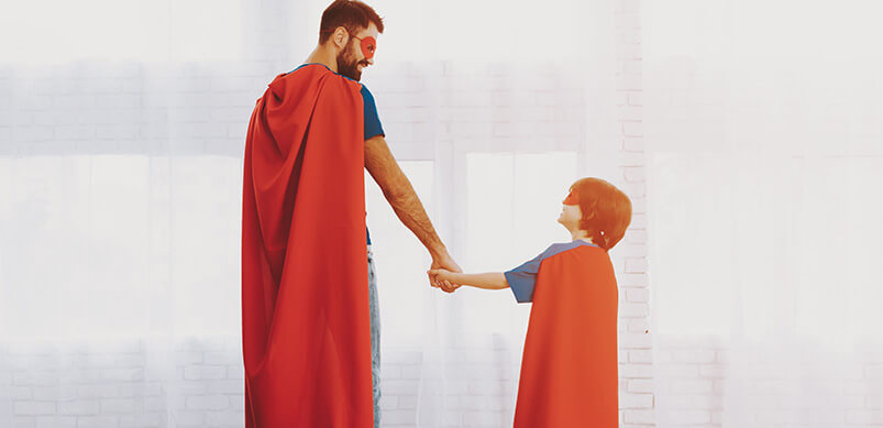 Father And Son In Superhero Capes Holding Hands