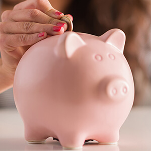 Woman Putting Coin In Piggy Bank