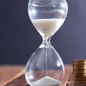 Hourglass With Coins On Table