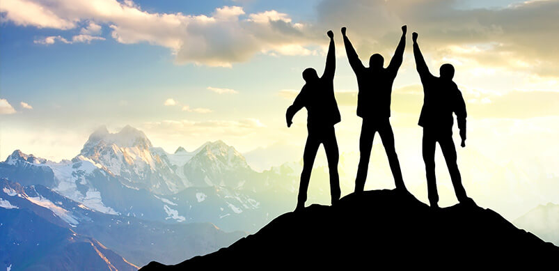 Three Friends Holding Hands At Top Of Mountain