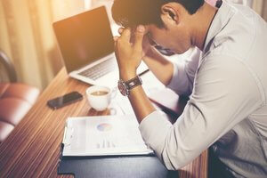 Man at desk with head in hands