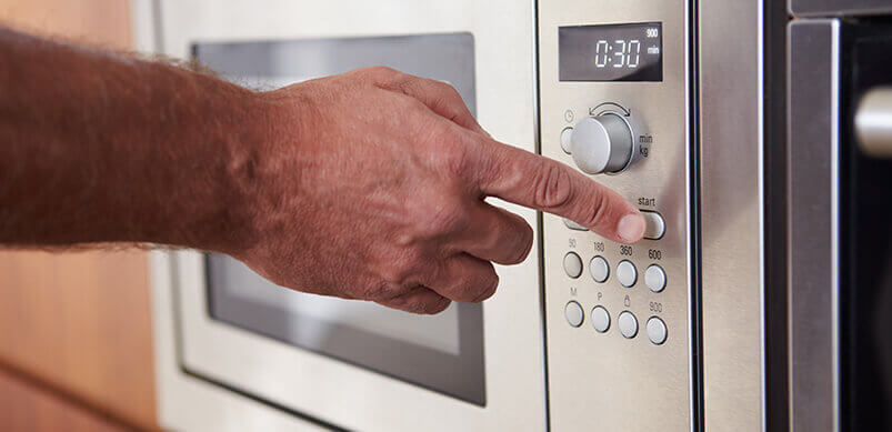 Man Pressing Button On Microwave