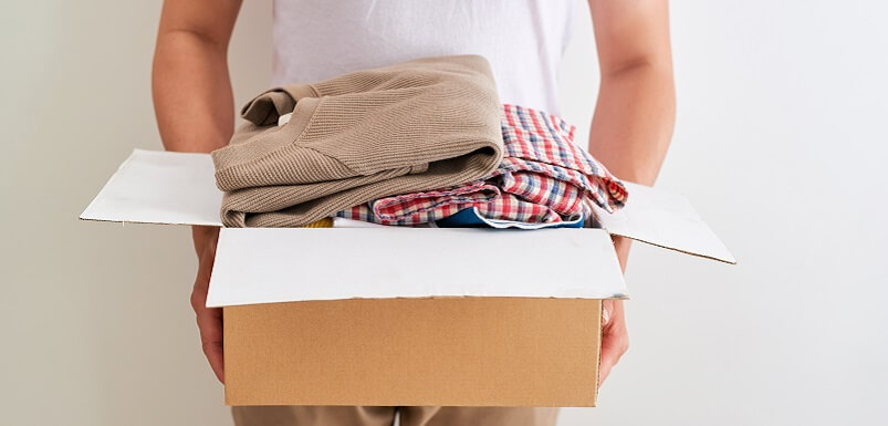 Man Holding Box Full Of Clothing