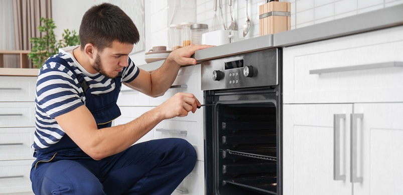 Young man repairing oven