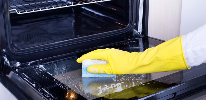 Gloved hand cleaning oven