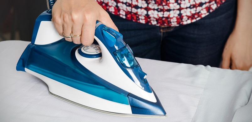 Woman ironing bed sheets