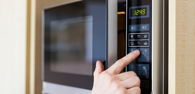 Hand pressing button on microwave