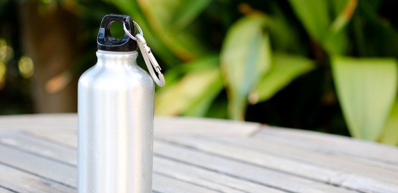 Reusable water bottle on a wooden table outdoors